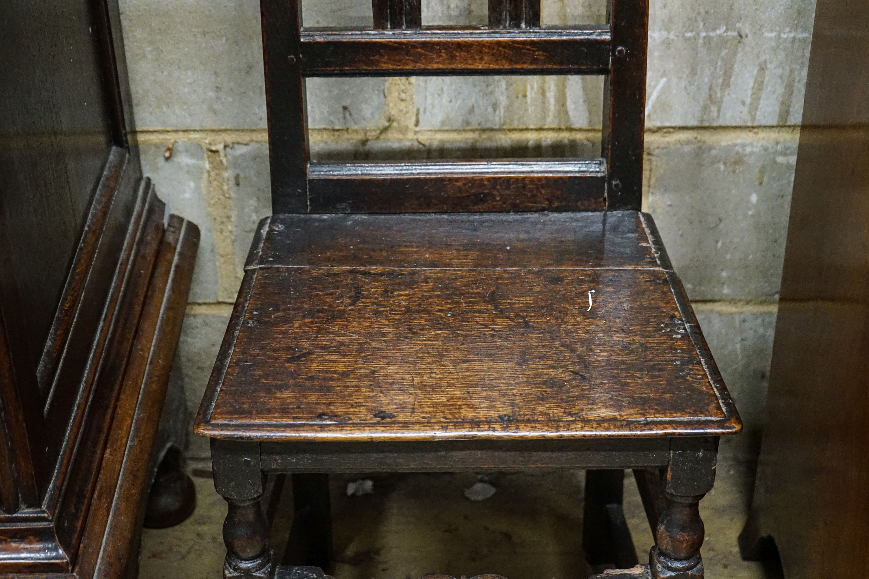 A late 17th century oak back stool, with carved cresting rail, slatted back and solid seat, on turned and square underframe, width 45cm, height 107cm